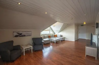 a living room with chairs and a couch and a tv at Seljevaagen Penthouse in Selje