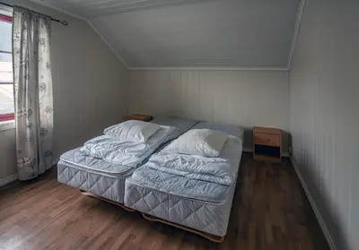 a small bedroom with a bed and a window at Seljevaagen Penthouse in Selje