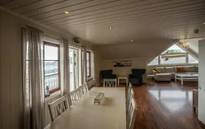 a living room with a table and chairs and a couch at Seljevaagen Penthouse in Selje
