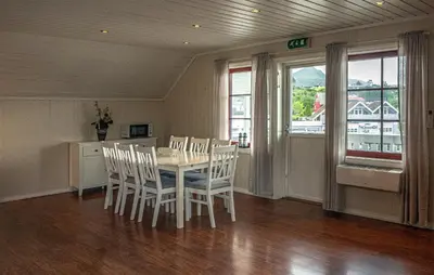 a dining room with a table and chairs and windows at Seljevaagen Penthouse in Selje
