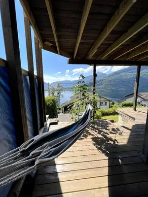a hammock on a porch with a view of the water at Fjord view apartment in Vaksdal