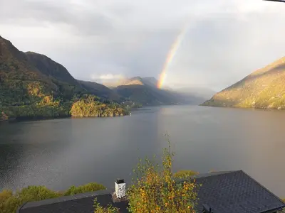 a rainbow over a lake with mountains in the background at Bluewater Cottage - Blåvannshytta in Bergen