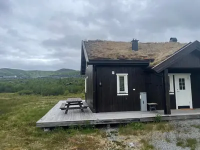 a small house with a picnic table on a deck at Modern Mountain Escape in Beitostøl
