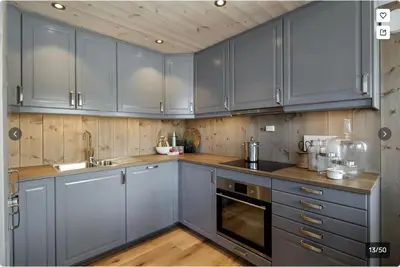 a kitchen with blue cabinets and wooden floors at Modern Mountain Escape in Beitostøl