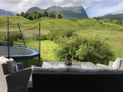 a living room with a table and a view of mountains at Stall Rygg Apartment, Gloppen