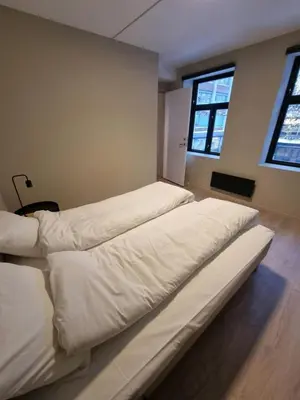 two large beds in a room with two windows at Central and Spacious Apartment for 6 in Trondheim