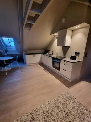 a kitchen with white cabinets and a table in a room at Central Studio for 2 in Trondheim