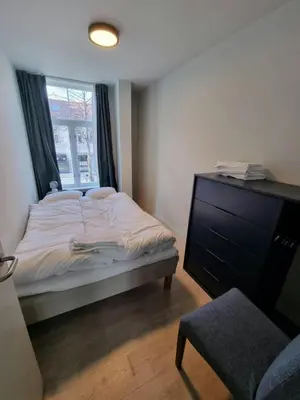 a bedroom with a bed and a dresser and a window at Central Apartment for 4 in Trondheim