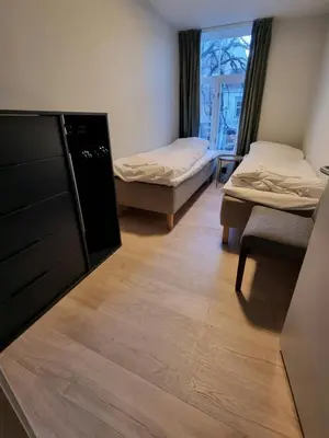 a room with two beds and a dresser and a window at Central Apartment for 4 in Trondheim
