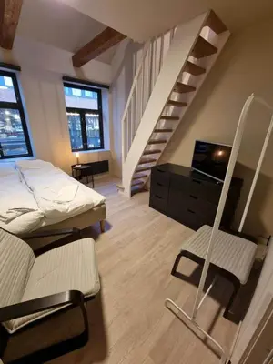 a bedroom with a bed and a stair case at Central and Spacious Apartment for 8 in Trondheim