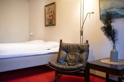 a bedroom with a bed and a chair and a table at Elvehagen Hotell in Sande