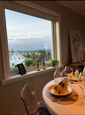 a table with two plates of food and a window at Koselig leilighet med utsikt, gåavstand fra sentrum in Stord