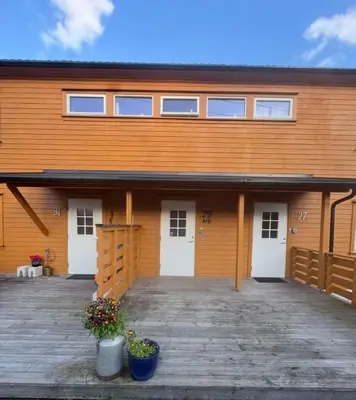 a building with two white doors and a porch at Koselig leilighet med utsikt, gåavstand fra sentrum in Stord