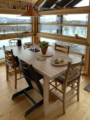 a wooden table and chairs in a room with windows at Modern Cabin With Views Of Hallingskarvet in Torpo