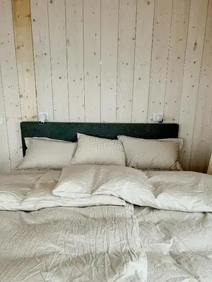 a large bed in a room with a wooden wall at Architectural Gem On Rocks In Kvenvær in Kvenvær