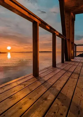 a wooden dock with the sun setting over the water at Architectural Gem On Rocks In Kvenvær in Kvenvær