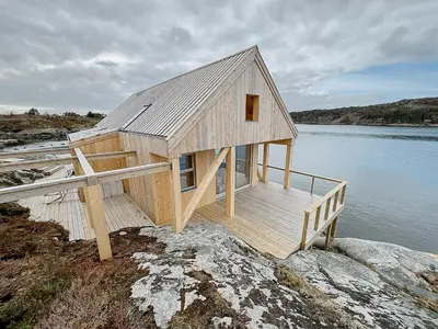 a wooden house on the edge of a body of water at Architectural Gem On Rocks In Kvenvær in Kvenvær