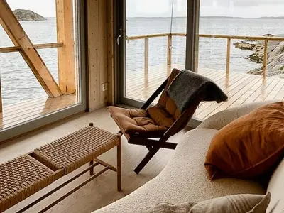 a living room with a rocking chair and a large window at Architectural Gem On Rocks In Kvenvær in Kvenvær