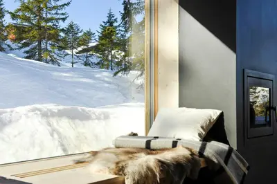a dog laying on a bed in front of a window at Modern Family Cabin With Trysil Mountain Views in Trysil