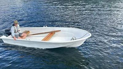 a person sitting in a white boat on the water at Living in a Nikolai Astrup motif 96m2 in Vassenden