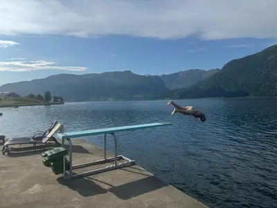a person jumping over a picnic table in a lake at Living in a Nikolai Astrup motif 96m2 in Vassenden