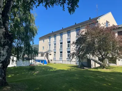 a large white building with a tree in front of it at Åndalsnes House---Apartments in Åndalsnes