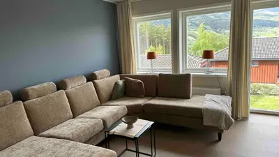 a living room with a large couch and two windows at Cozy house on Gryttingshaugen, near Vinstra in Sør-Fron