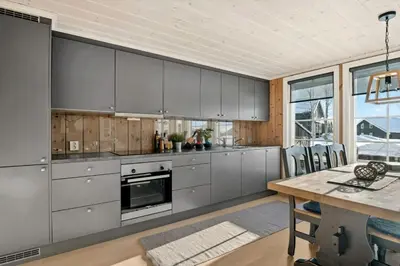 a kitchen with gray cabinets and a wooden table at Magiske Vinterdage I Sjusjøen in Mesnali