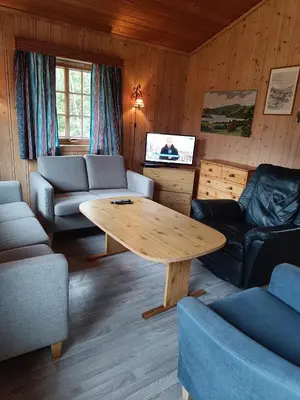 a living room with a table and couches and a tv at Stavn gård og hytter- 8 minutter til Bjørneparken in Flå
