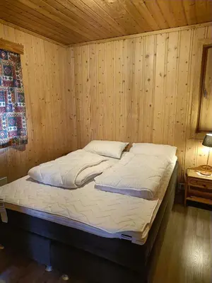a bed in a wooden room with a wooden wall at Stavn gård og hytter- 8 minutter til Bjørneparken in Flå