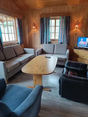 a living room with a table and couches and a tv at Stavn gård og hytter- 8 minutter til Bjørneparken in Flå
