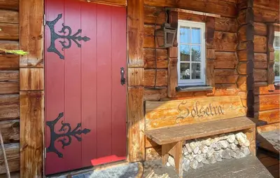 a red door on a log cabin with a bench at 4 Bedroom Gorgeous Home In Hovden I Setesdal in Hovden