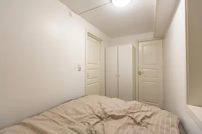 a white bedroom with a bed and two white closets at Kozy apartment near Bergen city center with free parking and Wifi in Bergen