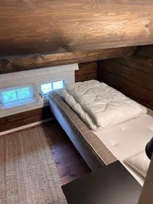 a bed in a room with wooden walls and windows at Sjarmerende tømmerhytte på Bjorli in Lii