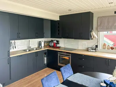 a kitchen with black cabinets and a table and chairs at Cabin With Sea Views In Mjømna