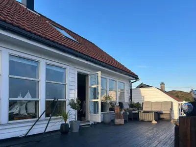 a house with a deck with a patio at Cabin With Sea Views In Mjømna
