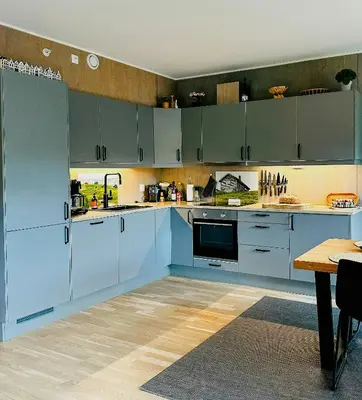 a large kitchen with blue cabinets and a table at Mountain Apartment With Views In Myrkdalen in Vossestrand