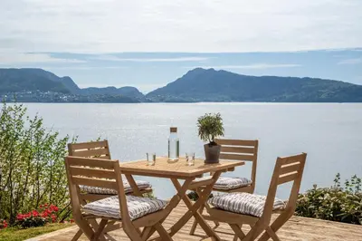 a wooden table and chairs on a deck with a view of a lake at Panoramic view with private terrace in Bergen