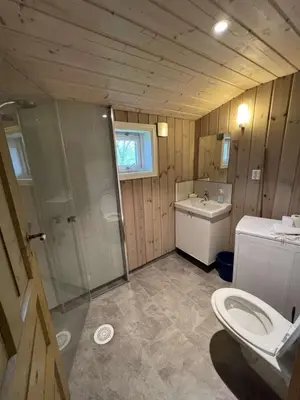a bathroom with a shower and a toilet and a sink at Gamlestova in Viksdalen