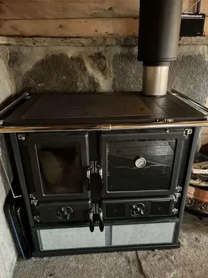 a black oven with a stove top on top at Gamlestova in Viksdalen