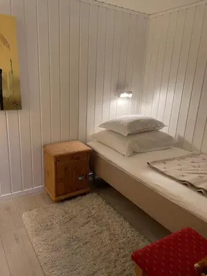 a bedroom with a bed and a wooden night stand at Sokkelleilighet med 3 soverom in Molde