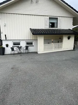 a garage with two chairs in front of a house at Sokkelleilighet med 3 soverom in Molde