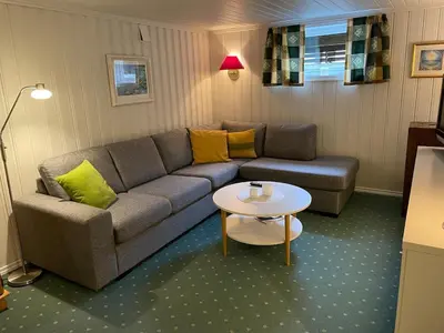 a living room with a couch and a table at Sokkelleilighet med 3 soverom in Molde