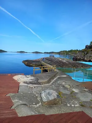 a dock with rocks in the water next to the water at New Modern House by the Sea in Askøy