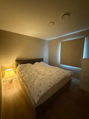 a small bedroom with a bed and a lamp at New Modern House by the Sea in Askøy