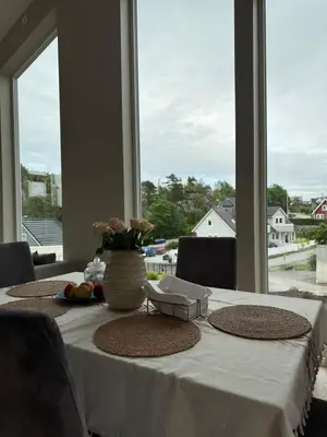 a table with a white table cloth and a large window at New Modern House by the Sea in Askøy
