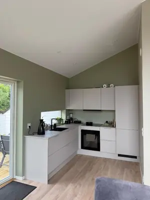 a kitchen with white cabinets and a large window at New Modern House by the Sea in Askøy