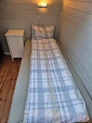 a bed in a tiny house with a side table at Idyllic house with views - close to nature in Nydalen