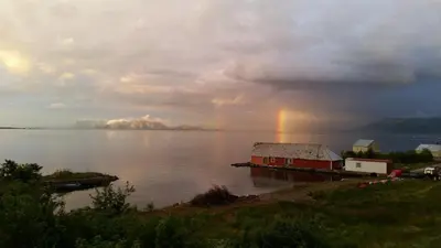 a rainbow over a large body of water with a house at Newly renovated apartment in beautiful Haramsøy in Ålesund