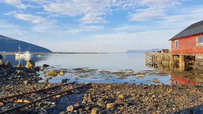 a red building on the shore of a body of water at Newly renovated apartment in beautiful Haramsøy in Ålesund